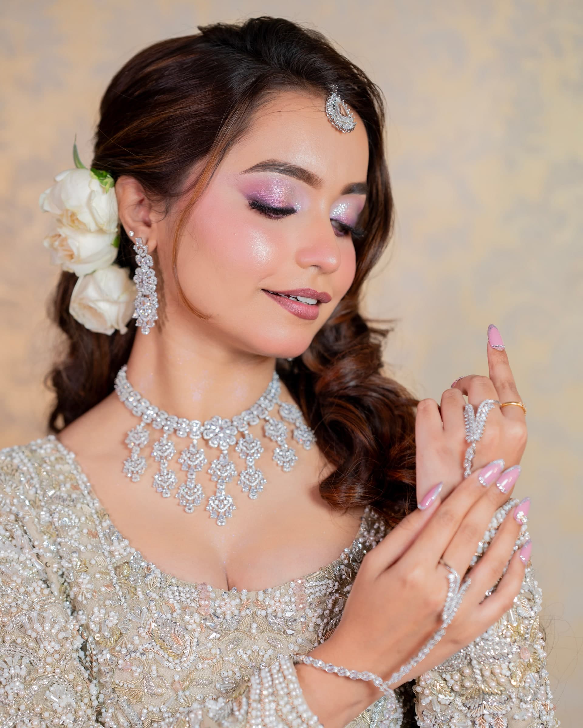Reception look in an embellished silver gown with diamond jewellery, white roses in the hair and shimmering lilac eye makeup