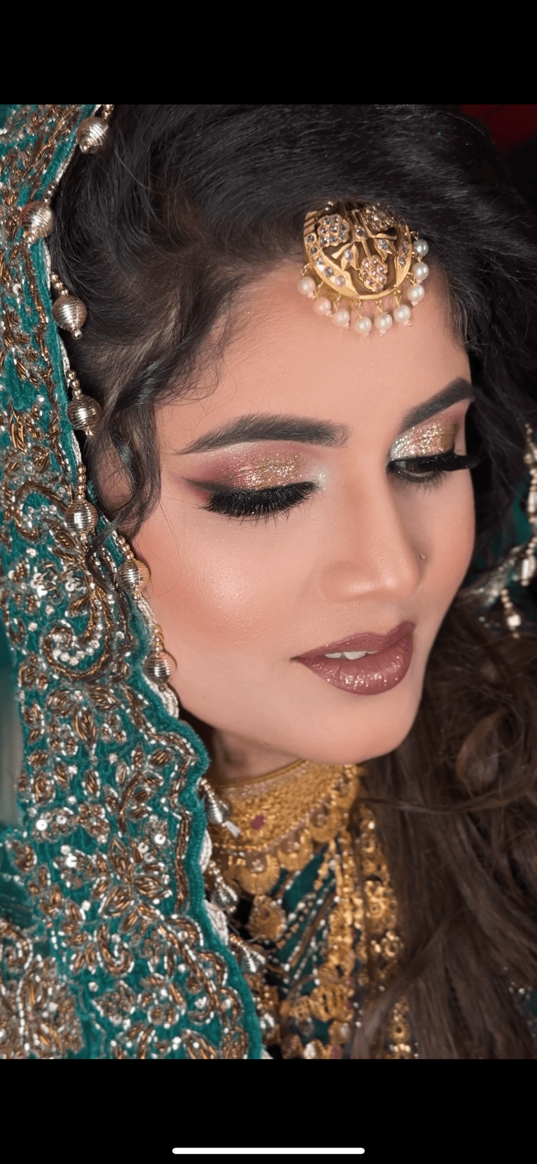 Bridal portrait in an emerald green embroidered lehenga and gold passa, with dramatic gold glitter eye makeup