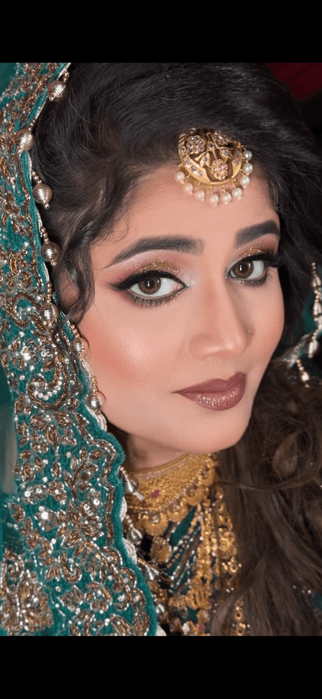 Close-up bridal portrait in emerald green and gold jewellery with winged liner and soft glossy lips