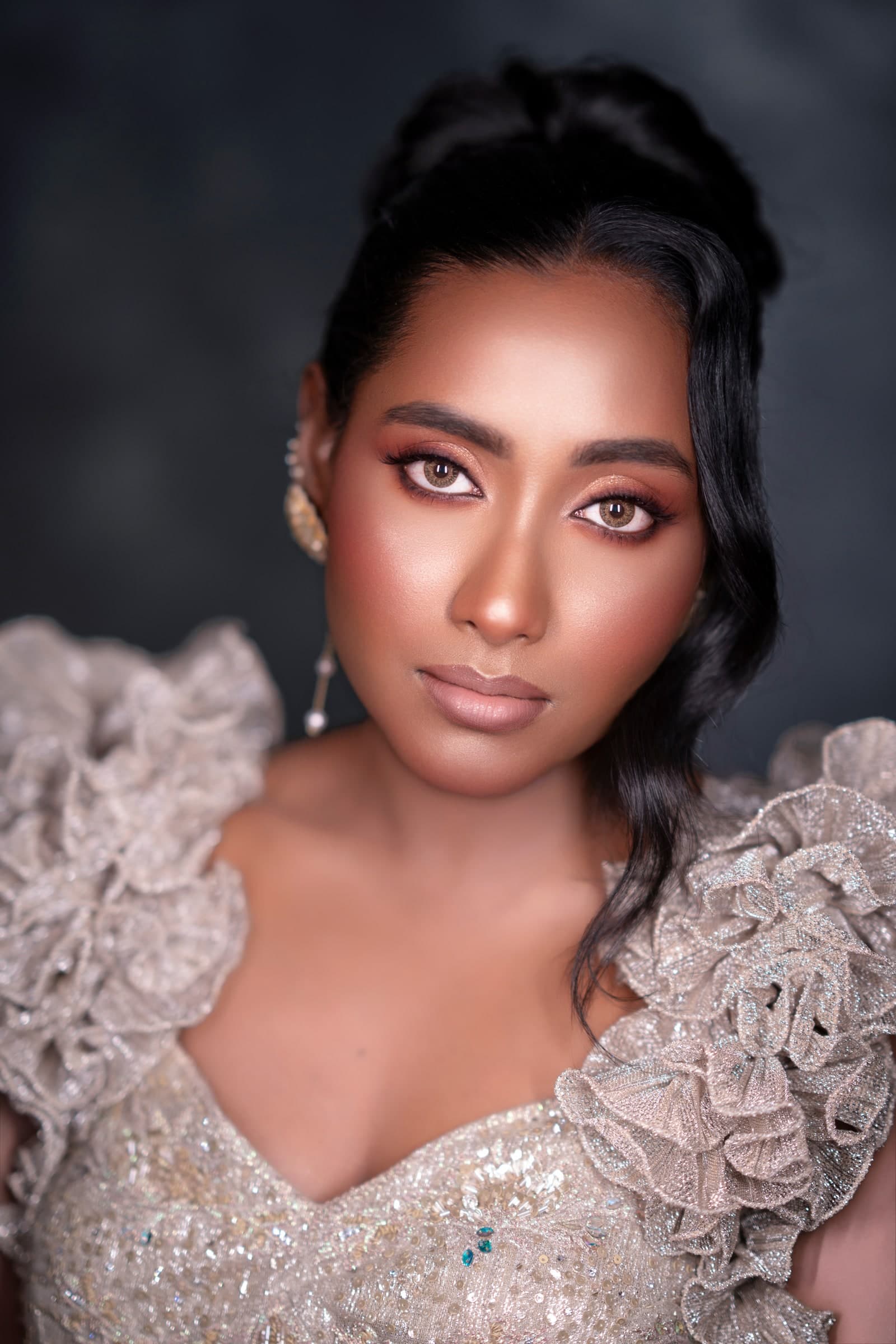 Editorial studio portrait in a metallic ruffled couture gown with sculpted nude makeup and bronze eyes