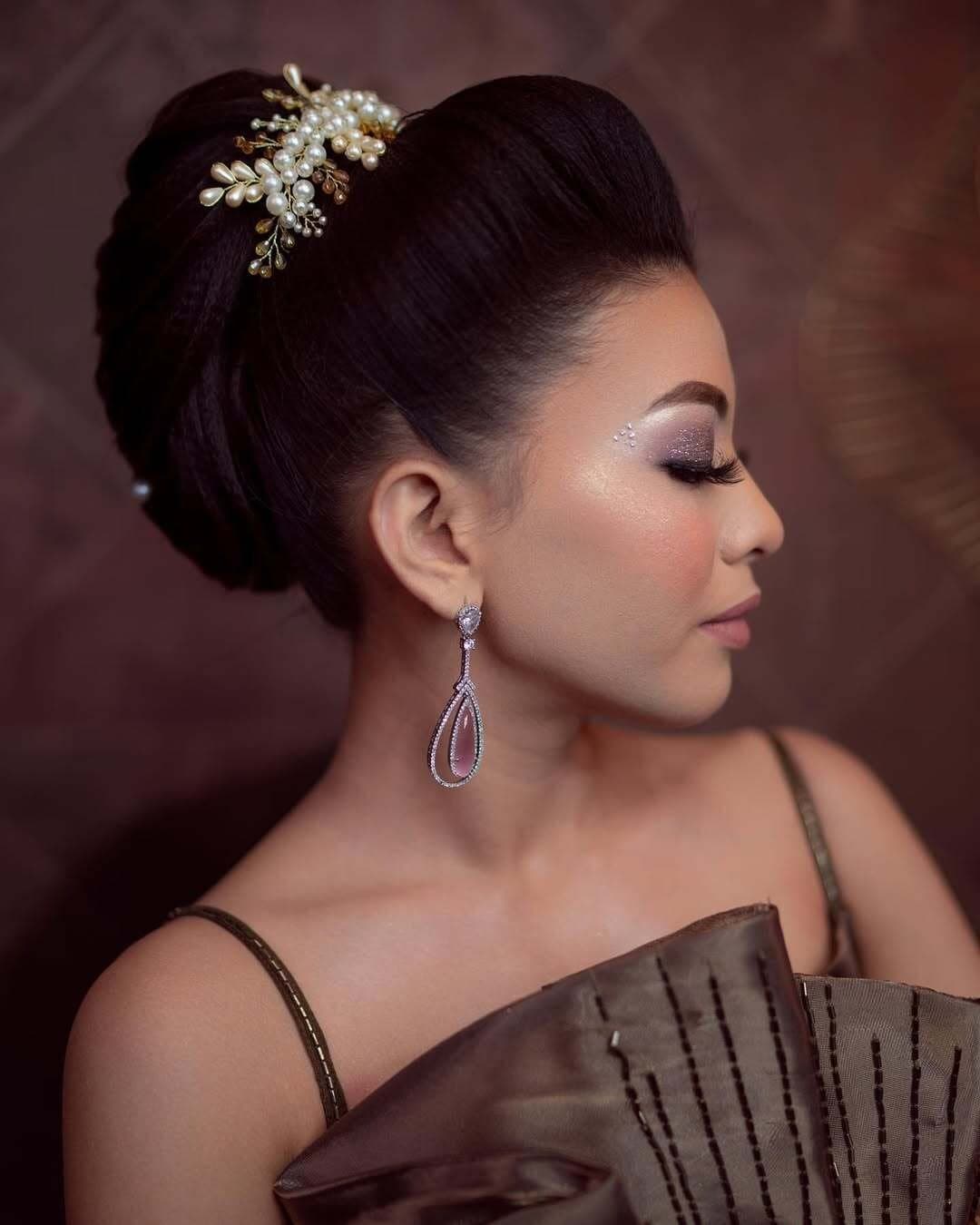 Profile of a sleek low bun with a jewelled hair accessory and statement earrings