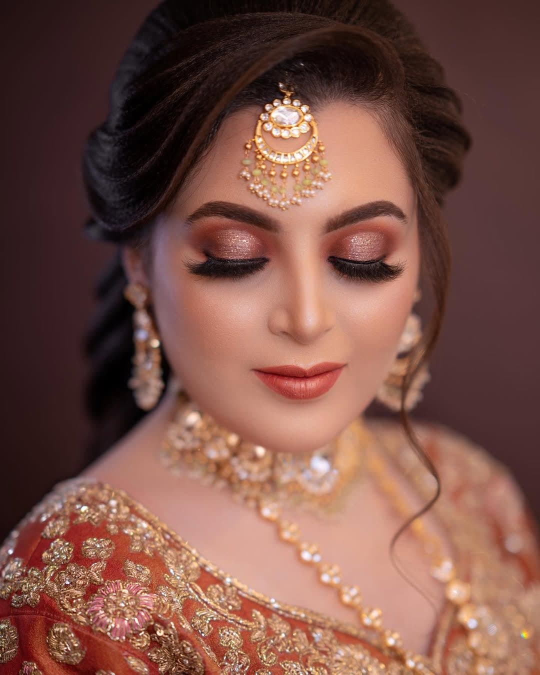 Reception look with soft bronze eyes, peach lips and a gold matha patti